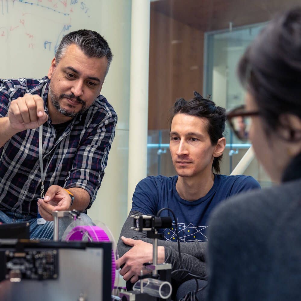 A group of researchers gathered around a table discussing science
