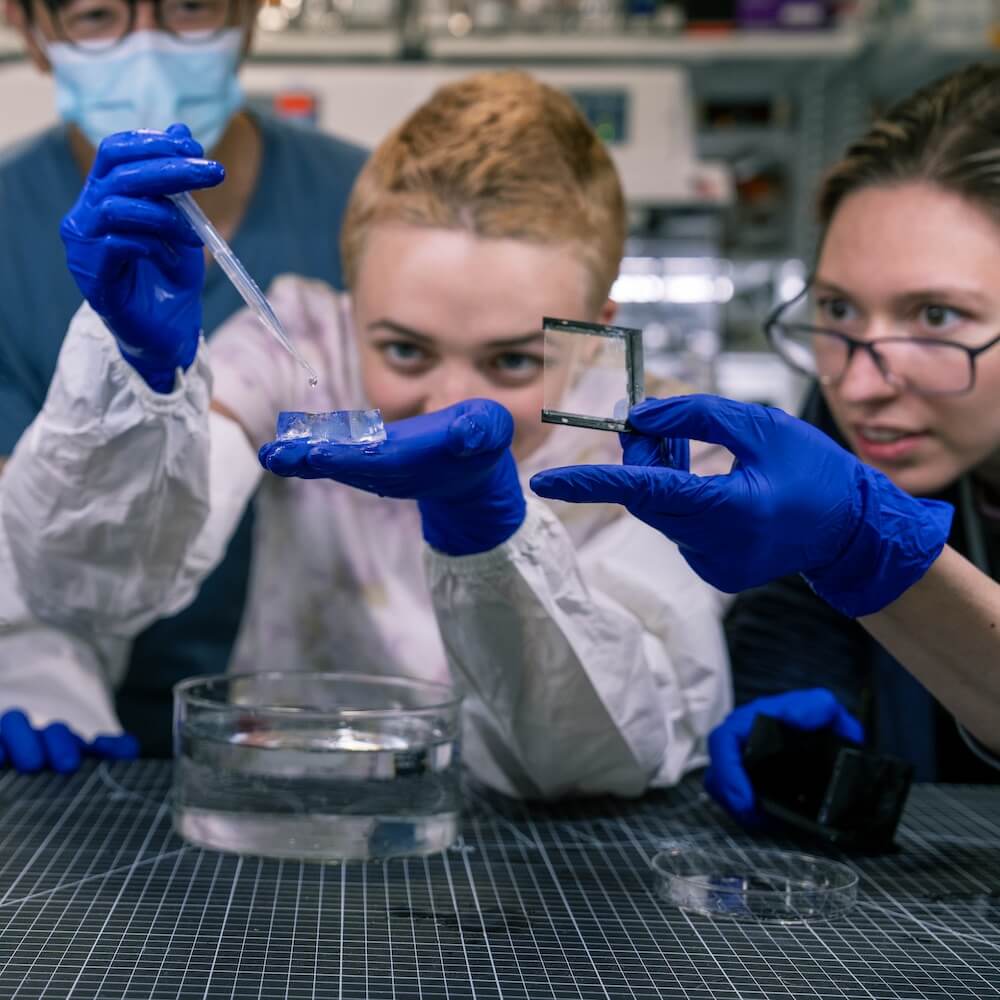 Scientists gathering around performing an experiment together.