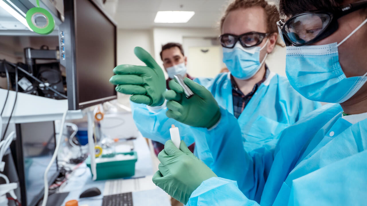 Windy Ho (right) and Michael Clark (center) prepare a living piece of human brain, removed during surgery and donated by the patient to science, for experiments at the Allen Institute. Brian Lee, Ph.D. (left), a scientist in the electrophysiology lab at the Allen Institute, looks on in the background. Photo by Erik Dinnel / Allen Institute