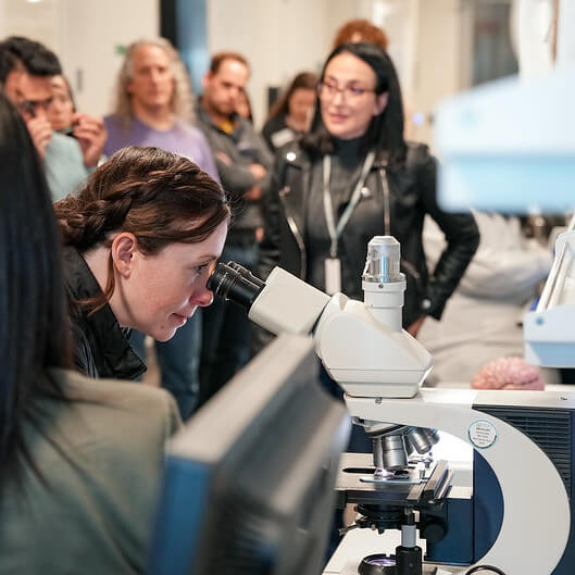 Teacher looking through a microscope during a tour of the Allen Institute