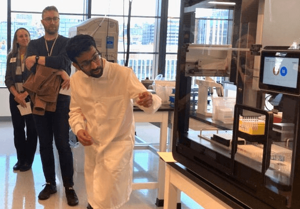 Scientist at the Seattle Hub for Synthetic Biology explaining how one of their machines works to a crowd